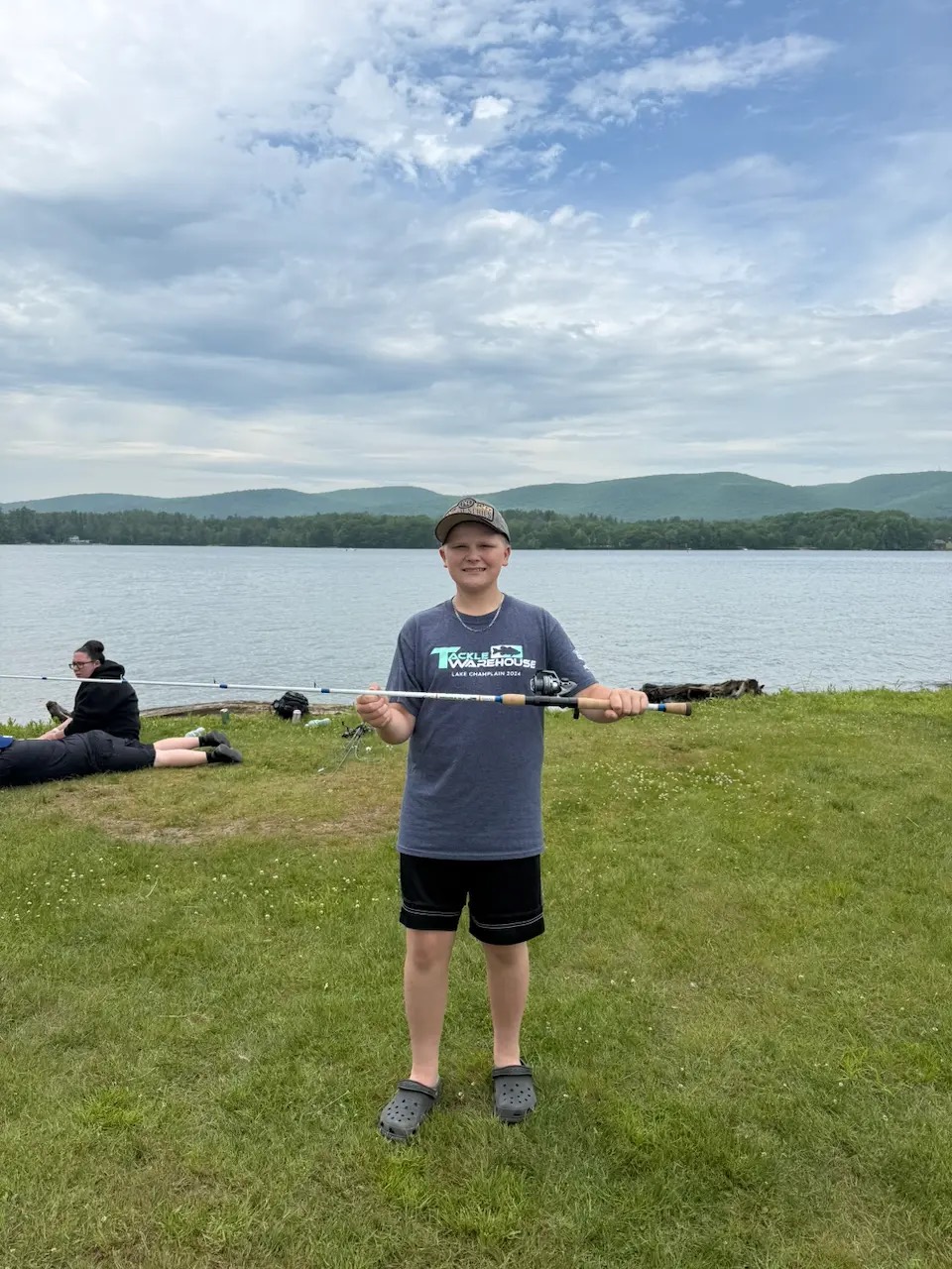 The 2026 Jimmy Fund Rod winner holding his rod beside a lake at the Harry A. Bateman Memorial Fishing Derby